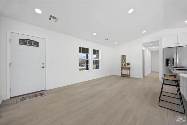 a kitchen with stainless steel appliances kitchen island granite countertop a stove a sink a refrigerator and white cabinets with wooden floor