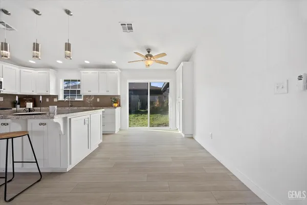 a view of kitchen with stainless steel appliances granite countertop a stove top oven a refrigerator a sink and a dining table with wooden floor