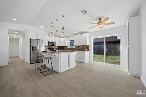a kitchen with kitchen island a stove a sink a refrigerator and cabinets