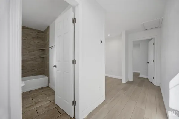 a view of an empty room with wooden floor and a ceiling fan