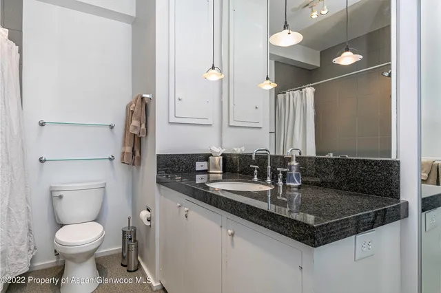 a bathroom with a granite countertop sink and a toilet