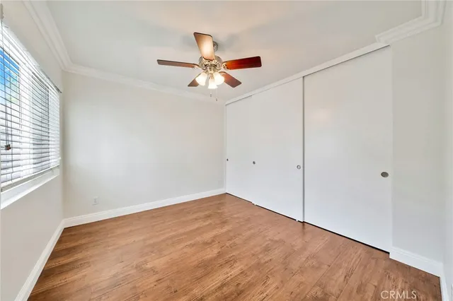 an empty room with wooden floor fan and windows