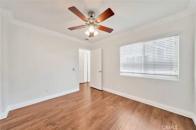 an empty room with wooden floor fan and windows