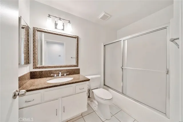 a bathroom with a granite countertop sink mirror vanity and toilet