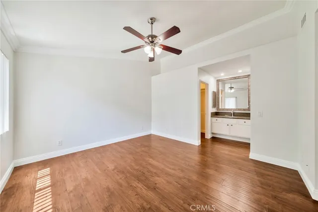 a view of empty room with wooden floor and ceiling fan