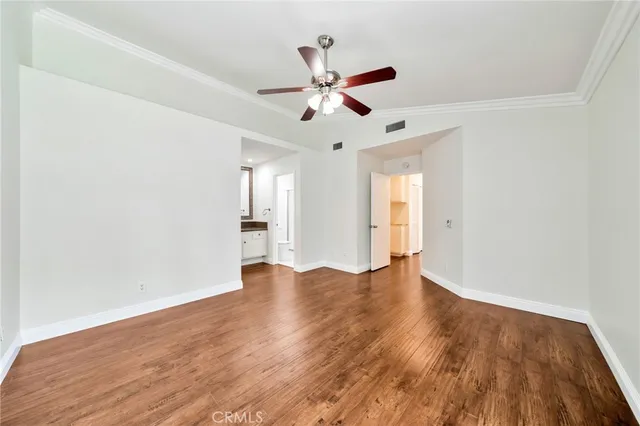 a view of empty room with wooden floor and fan