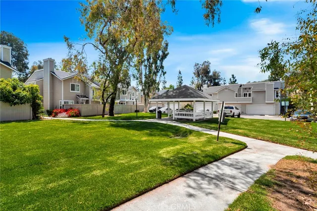 a view of a house with a big yard potted plants and large tree