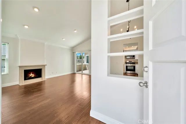 a view of a hallway with wooden floor and a kitchen