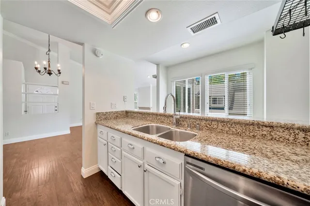 a kitchen with granite countertop a sink and wooden floors