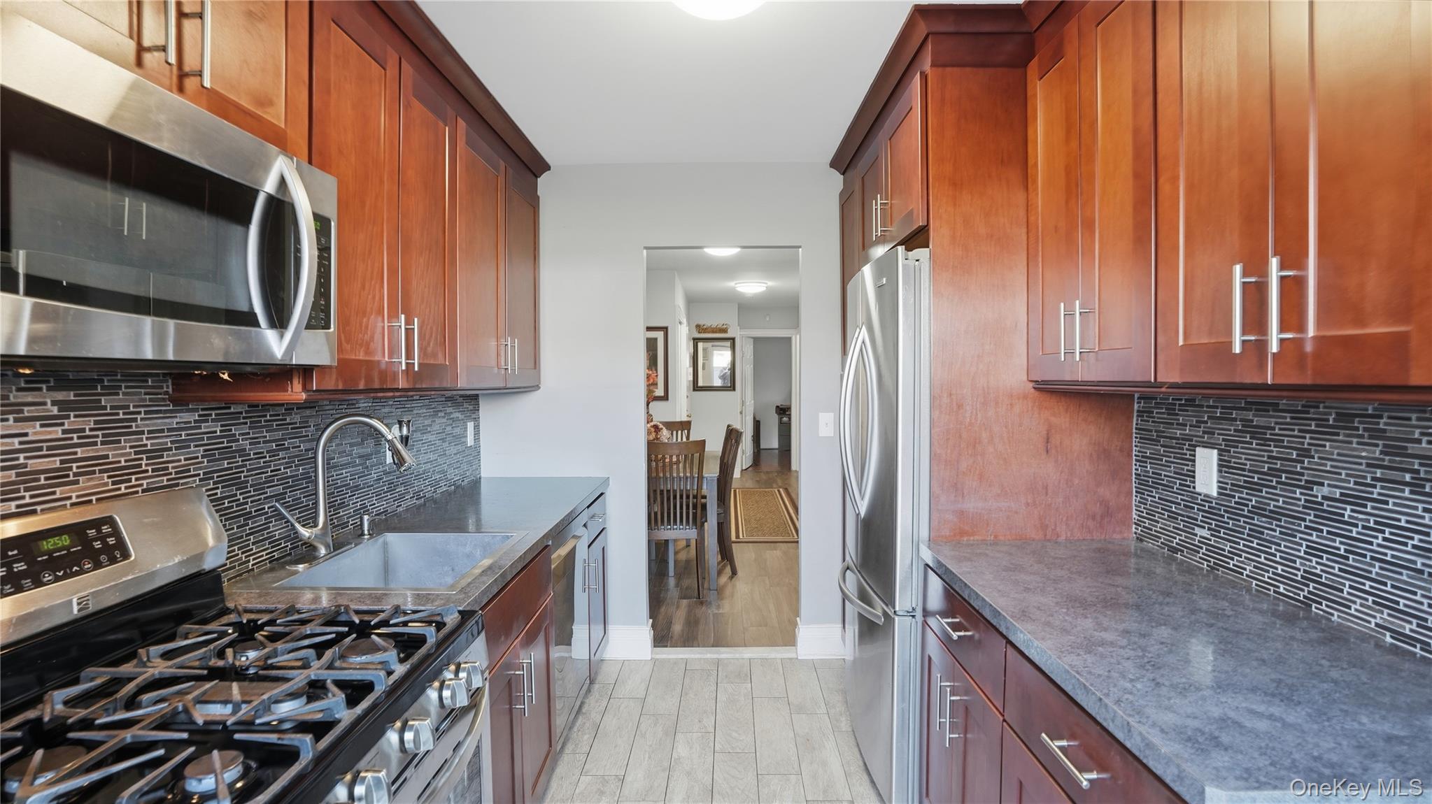 460 Old Town Road, Unit 28A East Setauket, NY 11766 - Photo 6 of 28 a kitchen with stainless steel appliances granite countertop a stove microwave and refrigerator