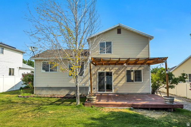 5529 Ridge Hollow Way Kearns, UT 84118 - Photo 21 of 23 Expansive backyard featuring a wood-finish deck with a pergola, sliding glass door access, and a manicured lawn