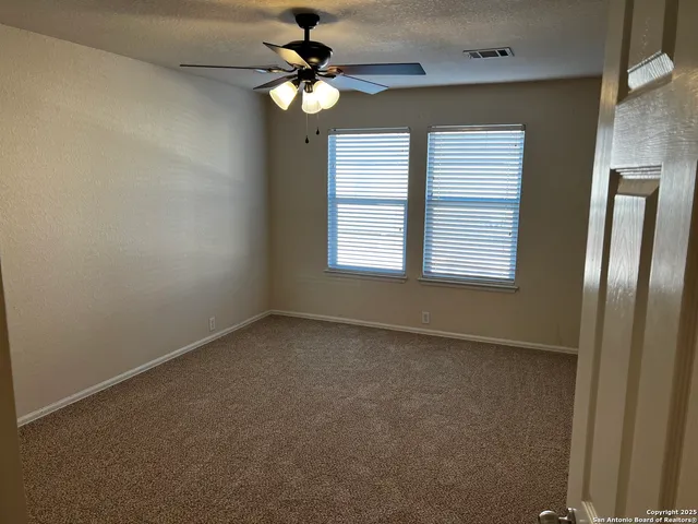 an empty room with windows and fan