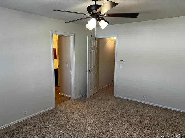 an empty room with closet and a chandelier fan