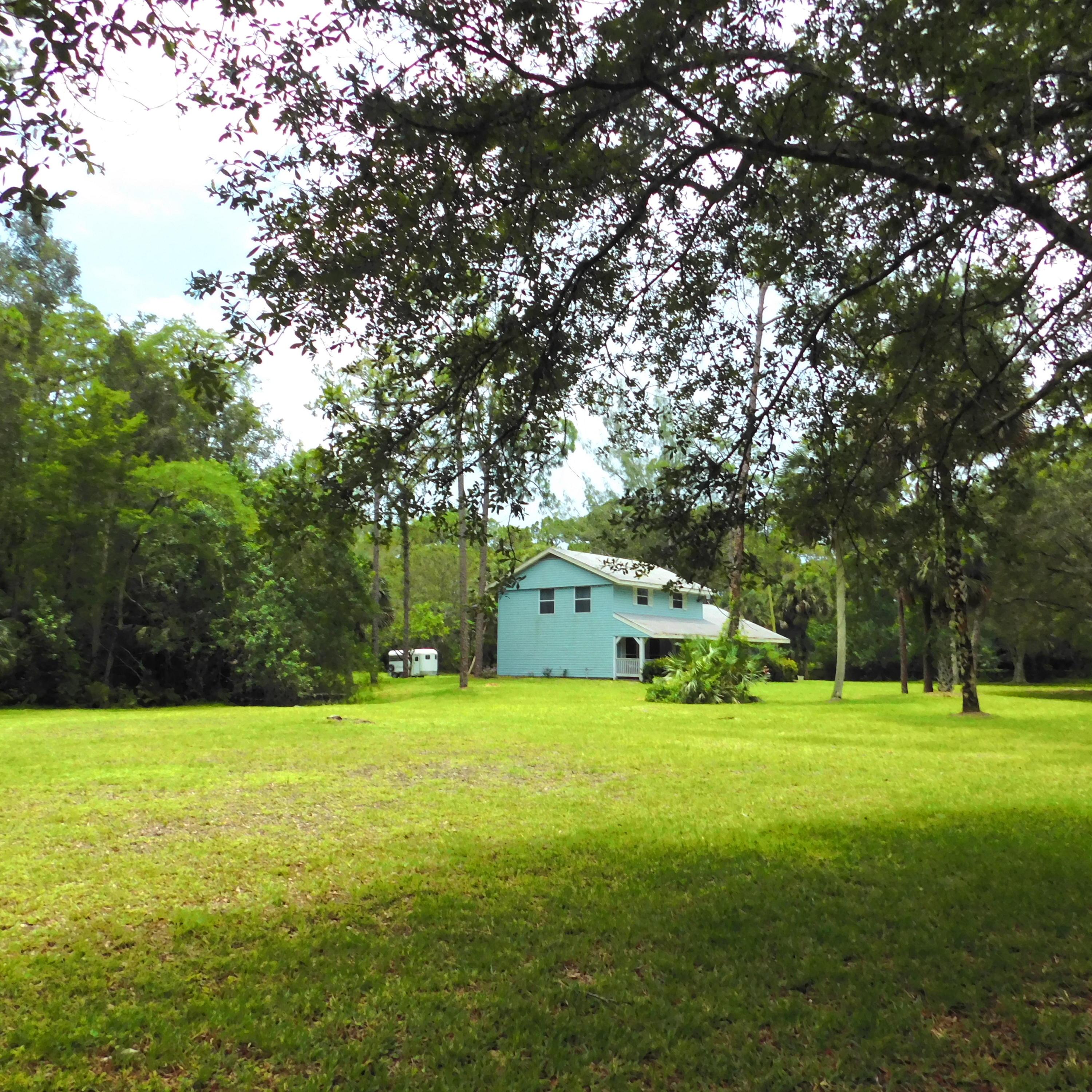 1032 Hyde Park Road Loxahatchee, FL 33470 - Photo 21 of 24 a view of a house with a big yard and large trees
