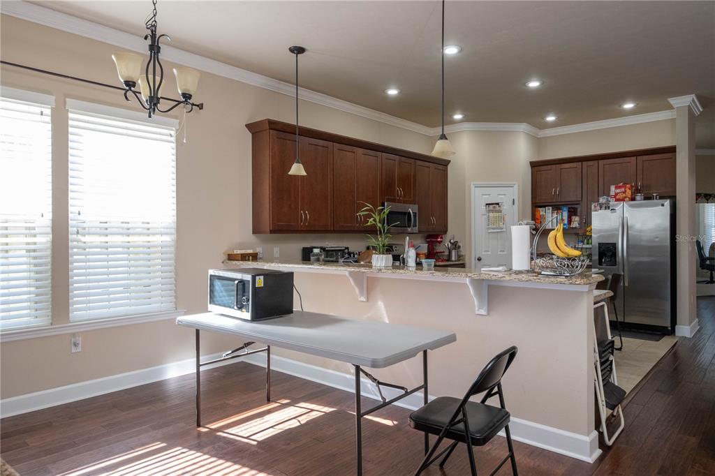 7775 Southwest 80th Drive Gainesville, FL 32608 - Photo 19 of 29 a kitchen with stainless steel appliances kitchen island granite countertop a refrigerator a stove a sink a dining table and chairs with wooden floor
