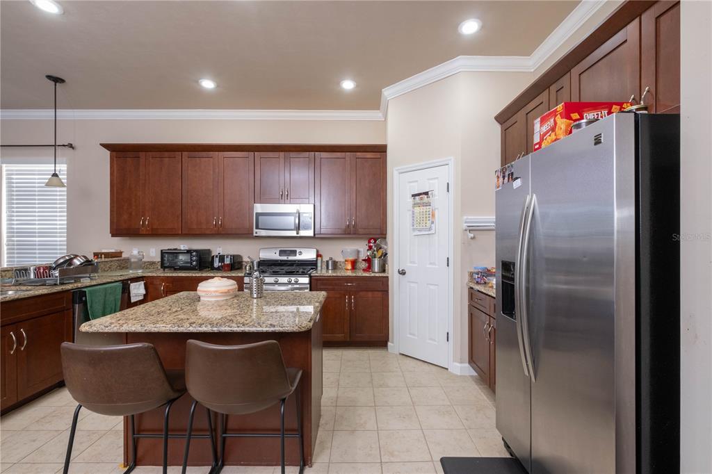 7775 Southwest 80th Drive Gainesville, FL 32608 - Photo 9 of 29 a kitchen with granite countertop a refrigerator and a stove top oven