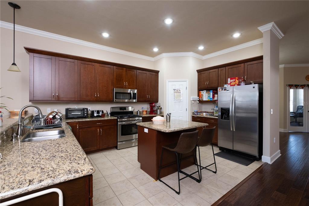7775 Southwest 80th Drive Gainesville, FL 32608 - Photo 10 of 29 a kitchen with stainless steel appliances granite countertop a sink stove refrigerator and cabinets