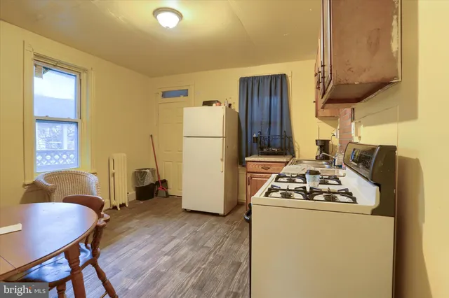 a kitchen with stainless steel appliances granite countertop a stove a refrigerator a sink dishwasher a dining table and chairs with wooden floor