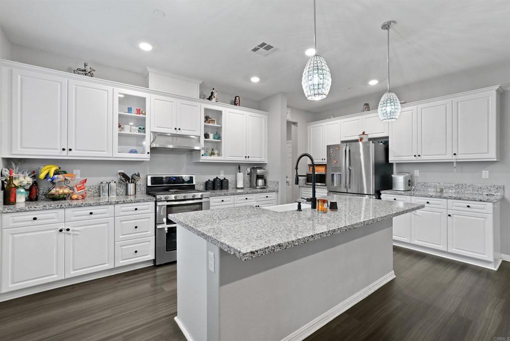 33009 Marin Fields Road Winchester, CA 92596 - Photo 17 of 51 a large kitchen with granite countertop a stove a sink a center island and cabinets