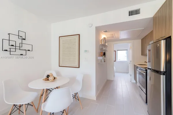a kitchen with stainless steel appliances refrigerator dining table and chairs