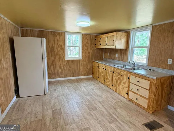 a kitchen with granite countertop a refrigerator a sink and white cabinets
