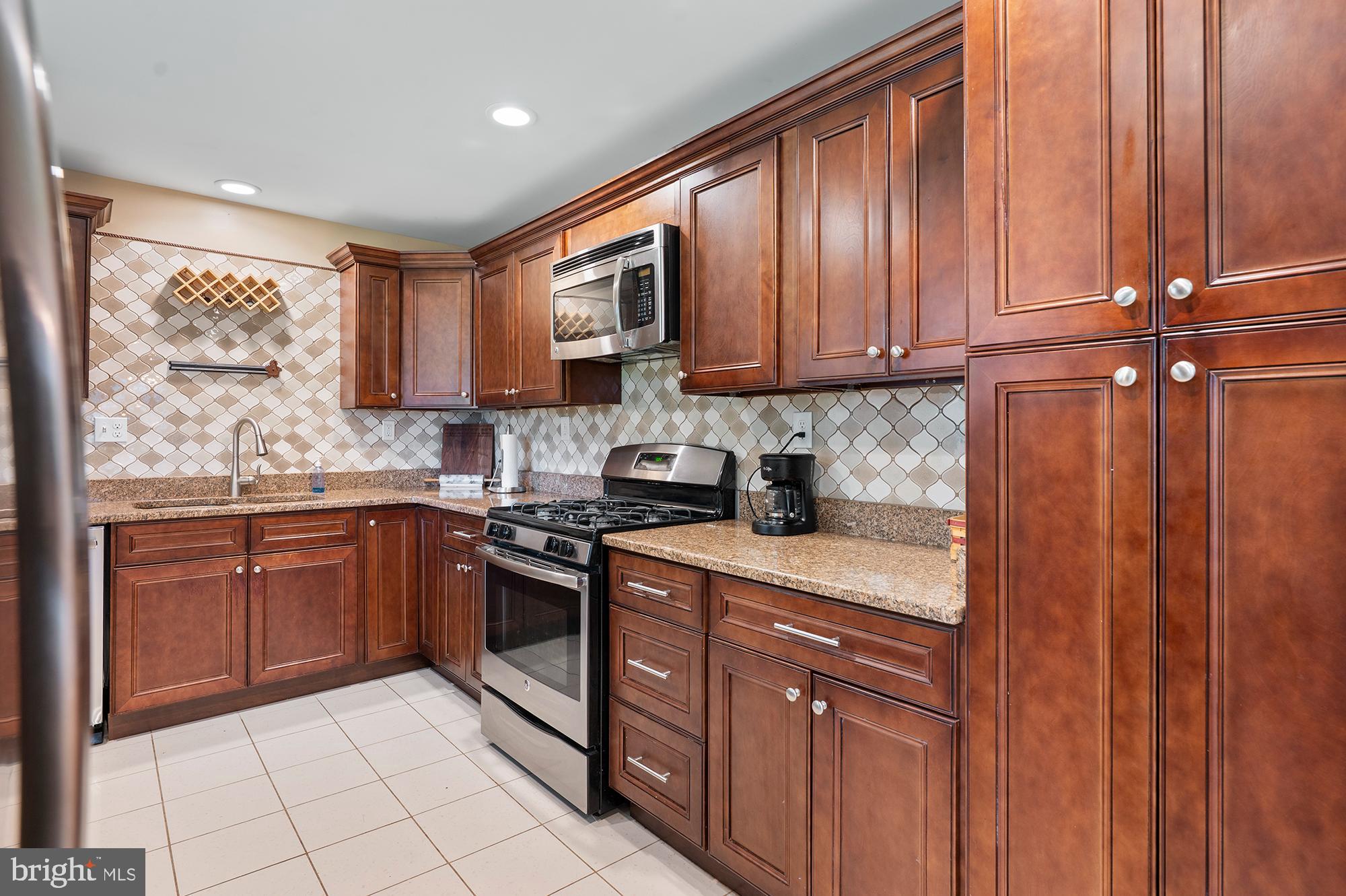 328 West Bay Front Road Lothian, MD 20711 - Photo 13 of 46 a kitchen with granite countertop wooden cabinets stainless steel appliances a sink and a window
