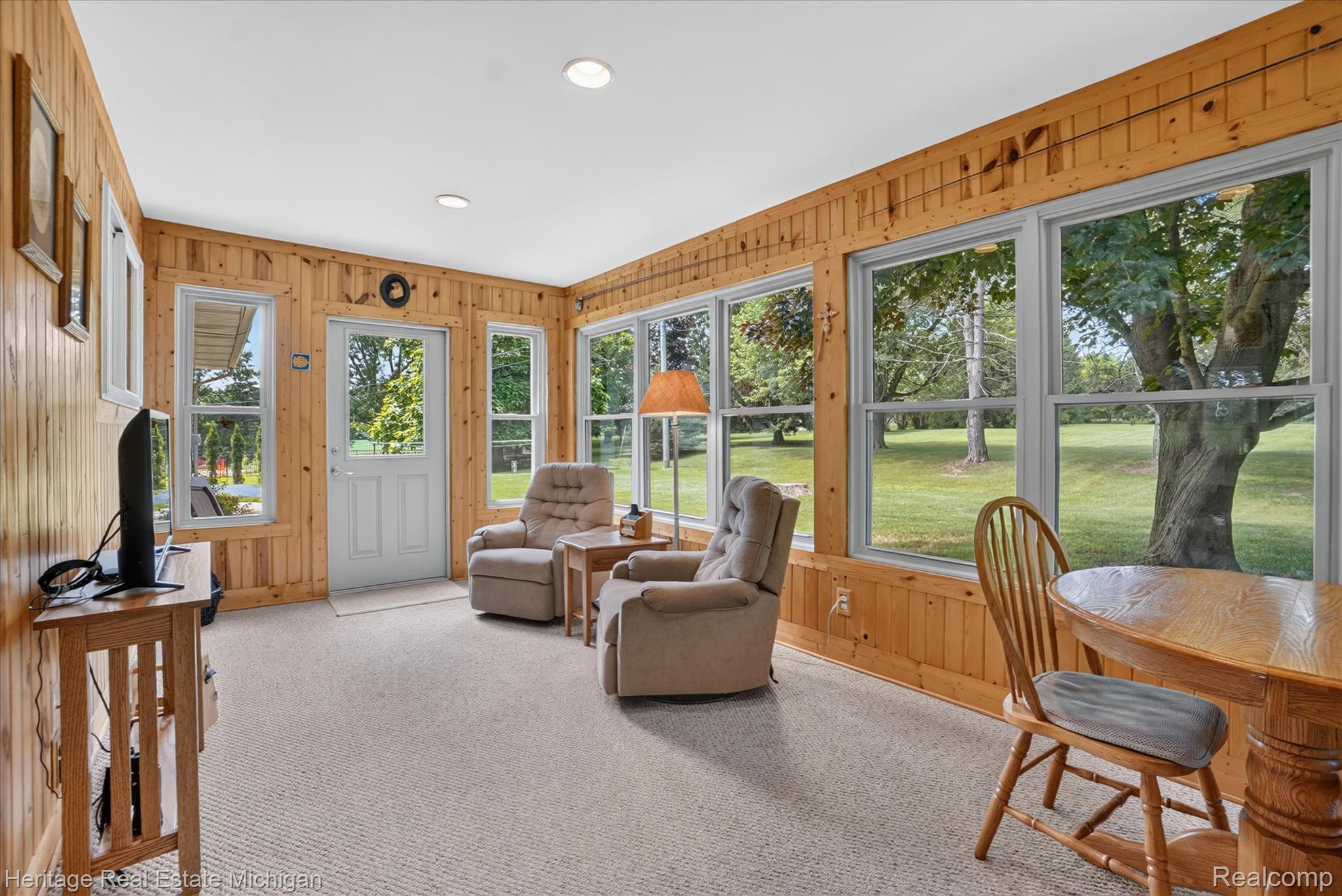 14038 North Hogan Road Linden, MI 48451 - Photo 22 of 53 Sunroom featuring extensive natural wood-paneled walls, multiple windows, a white paneled door, recessed lighting, and carpeted flooring