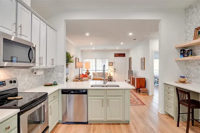 a kitchen with stainless steel appliances a sink a stove a refrigerator cabinets and wooden floor