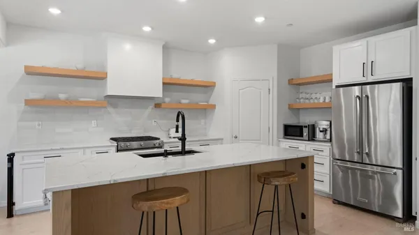 a kitchen with stainless steel appliances a sink a stove a refrigerator and white cabinets