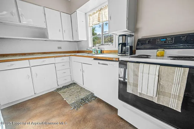 a kitchen with white cabinets and window