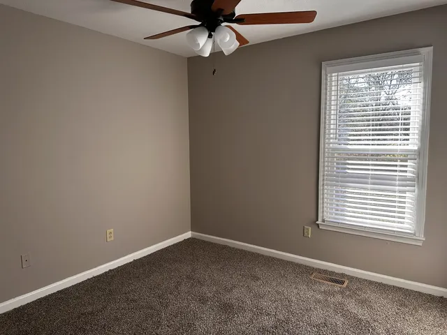an empty room with a window and a fan