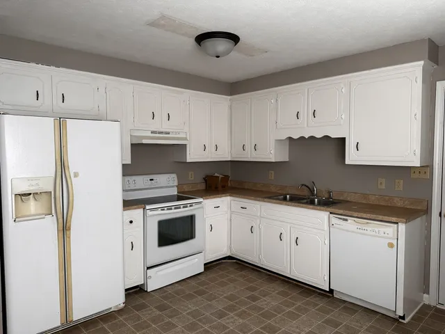 a kitchen with granite countertop white cabinets and white appliances