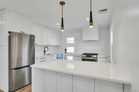 a kitchen with stainless steel appliances a refrigerator a stove a sink a center island and a cabinets