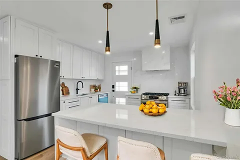 a kitchen with stainless steel appliances granite countertop a refrigerator a stove a sink a dining table and chairs