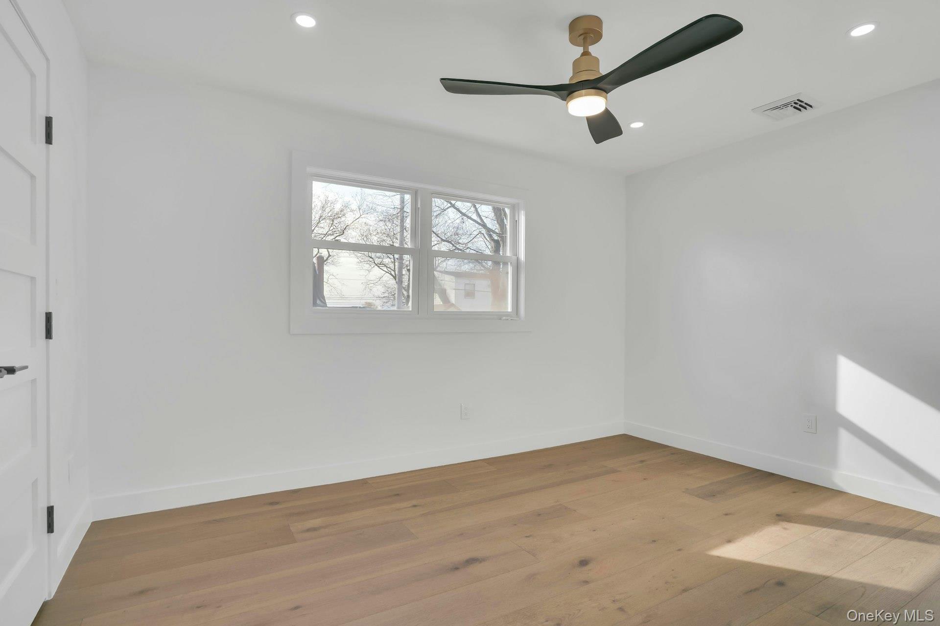 243 Lido Parkway Lindenhurst, NY 11757 - Photo 28 of 46 an empty room with wooden floor ceiling fan and windows