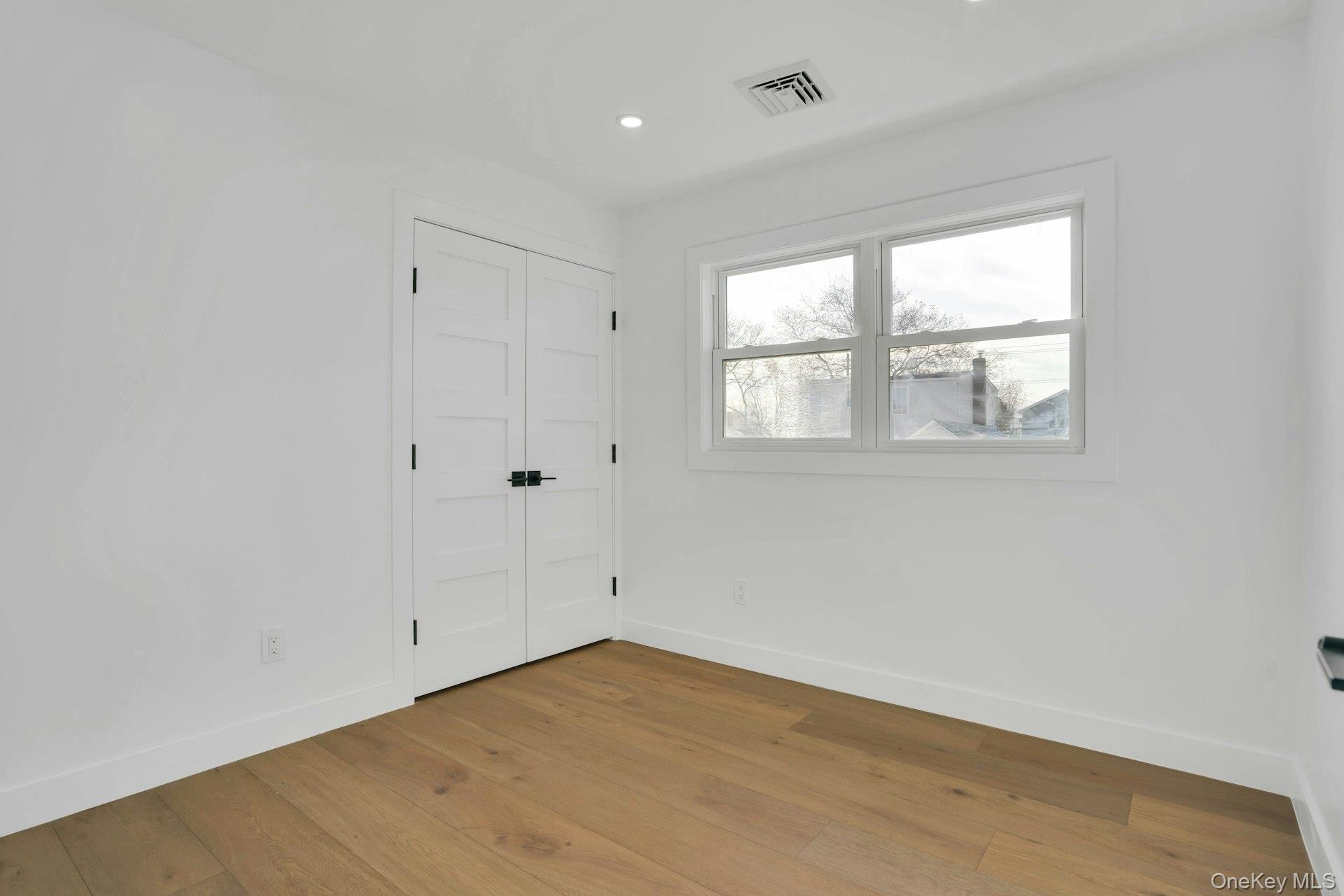 243 Lido Parkway Lindenhurst, NY 11757 - Photo 34 of 46 an empty room with wooden floor and windows