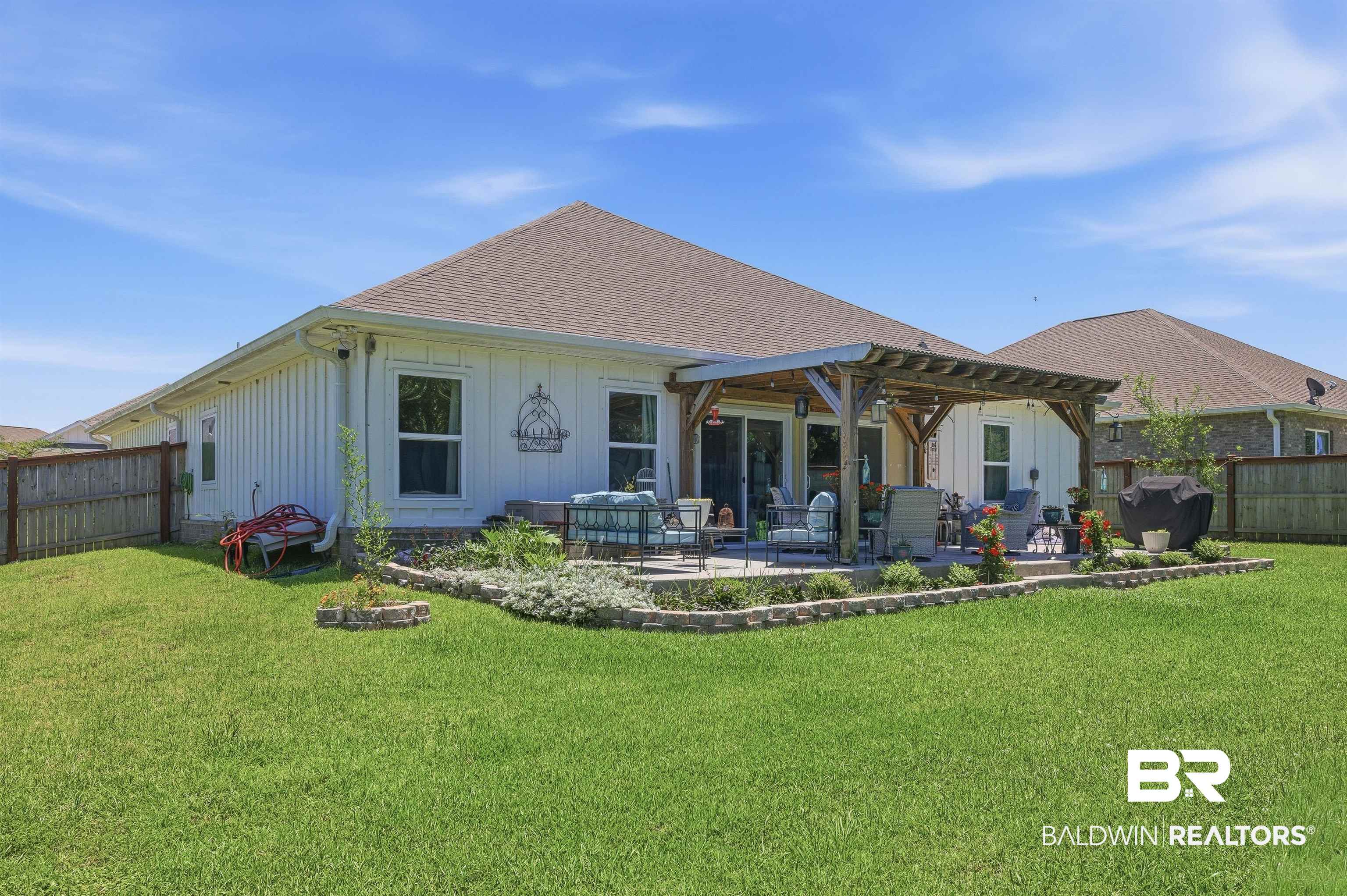 8735 Bronze Lane Foley, AL 36535 - Photo 44 of 58 Expansive backyard featuring a manicured lawn, a concrete patio, and a wooden pergola structure