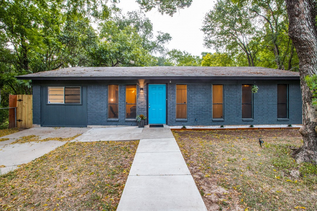 A vibrant blue door provides a welcoming focal point to this charming brick residence.