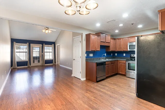 a kitchen with granite countertop a refrigerator and wooden floors