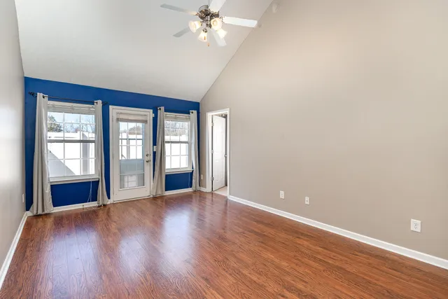a view of an empty room with wooden floor and a window