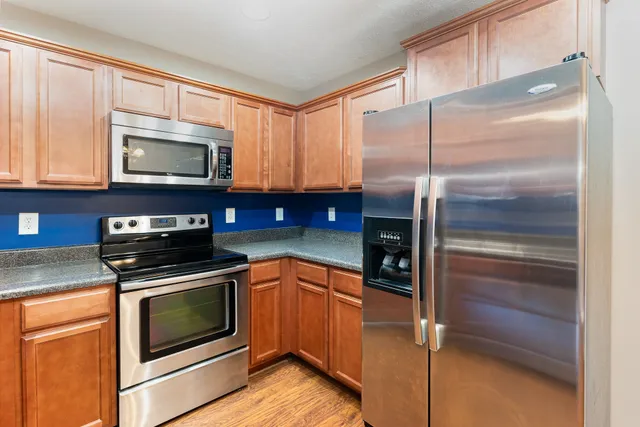 a kitchen with granite countertop wooden cabinets stainless steel appliances and a window