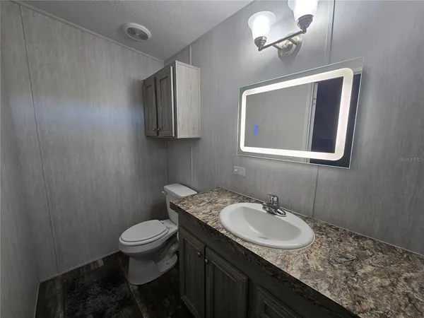 a bathroom with a granite countertop sink a toilet and mirror