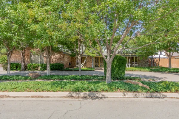 a front view of a house with a garden and trees