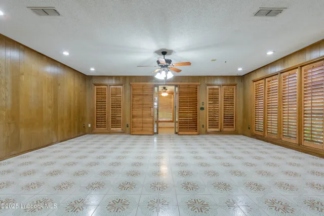 an empty room with wooden floor a ceiling fan and a fireplace