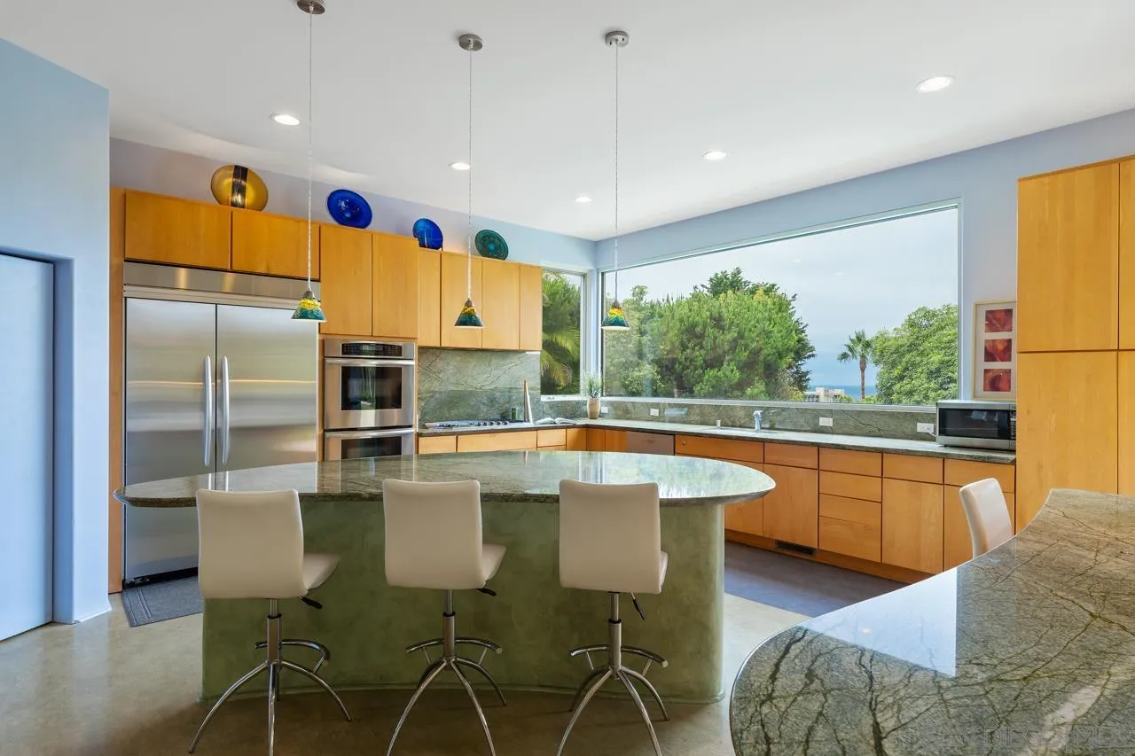 2626 Hidden Valley Road La Jolla, CA 92037 - Photo 38 of 54 a kitchen with stainless steel appliances granite countertop a table chairs stove and refrigerator
