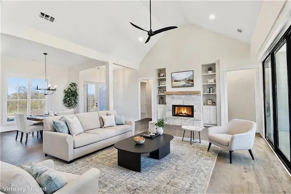 a view of a room with wooden floor ceiling fan and windows