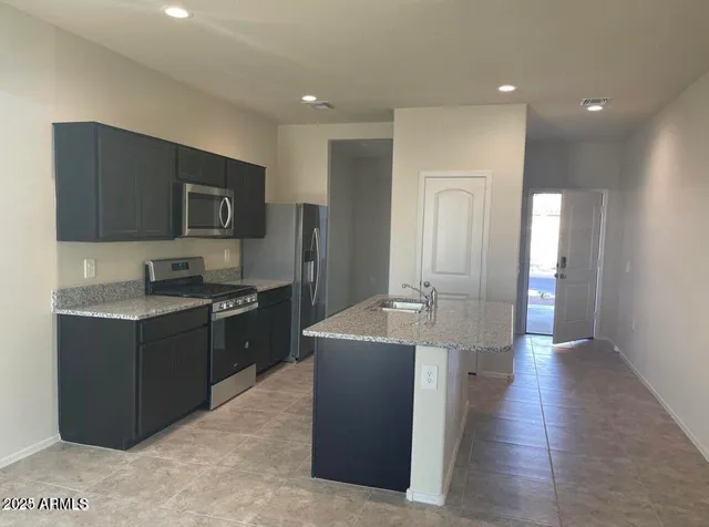 a large kitchen with stainless steel appliances a large counter top a stove a sink a refrigerator and a refrigerator