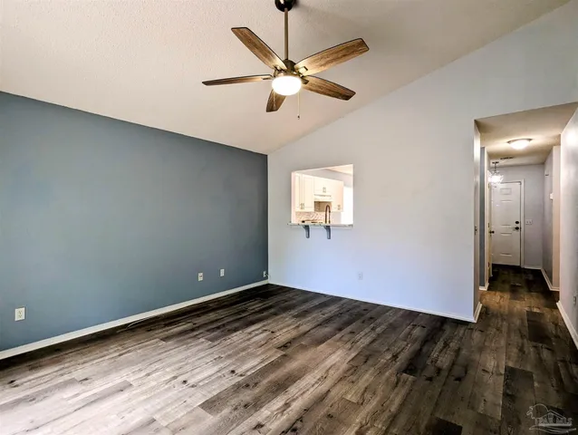 an empty room with wooden floor and fan