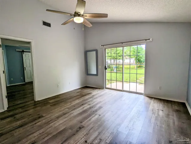 an empty room with wooden floor chandelier fan and windows