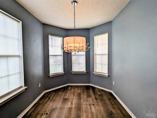 a view of an empty room with wooden floor and windows